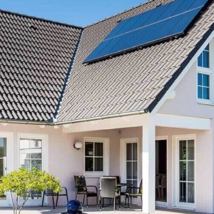 Haus mit vielen bodentiefen Fenstern, Dach mit Solarpanelen, Steinterrasse