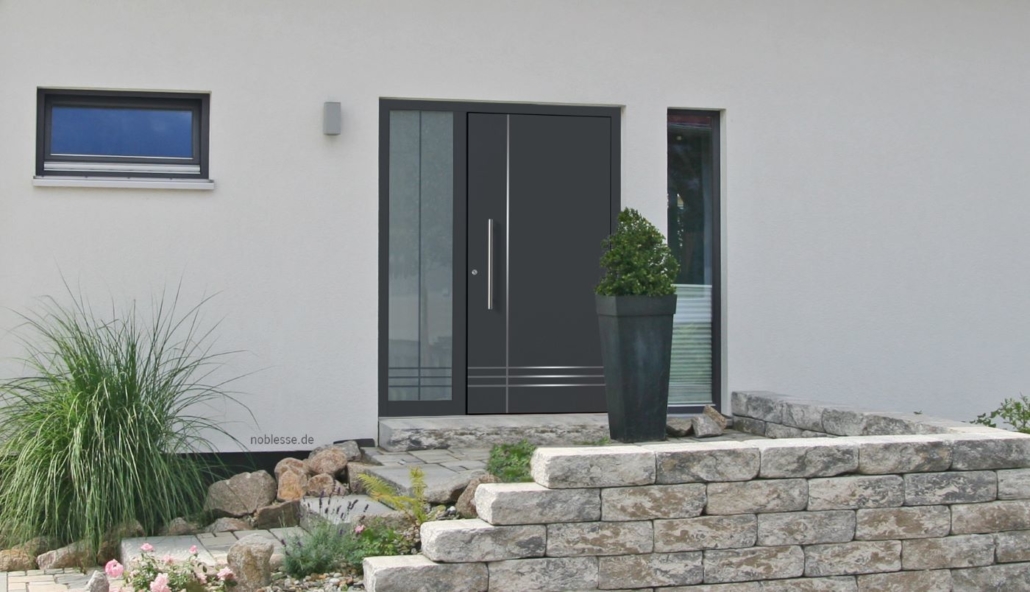 Haustür in anthrazit mit Einkerbungen aus Aluminium und einem Fensterausschnitt links, Steintreppe