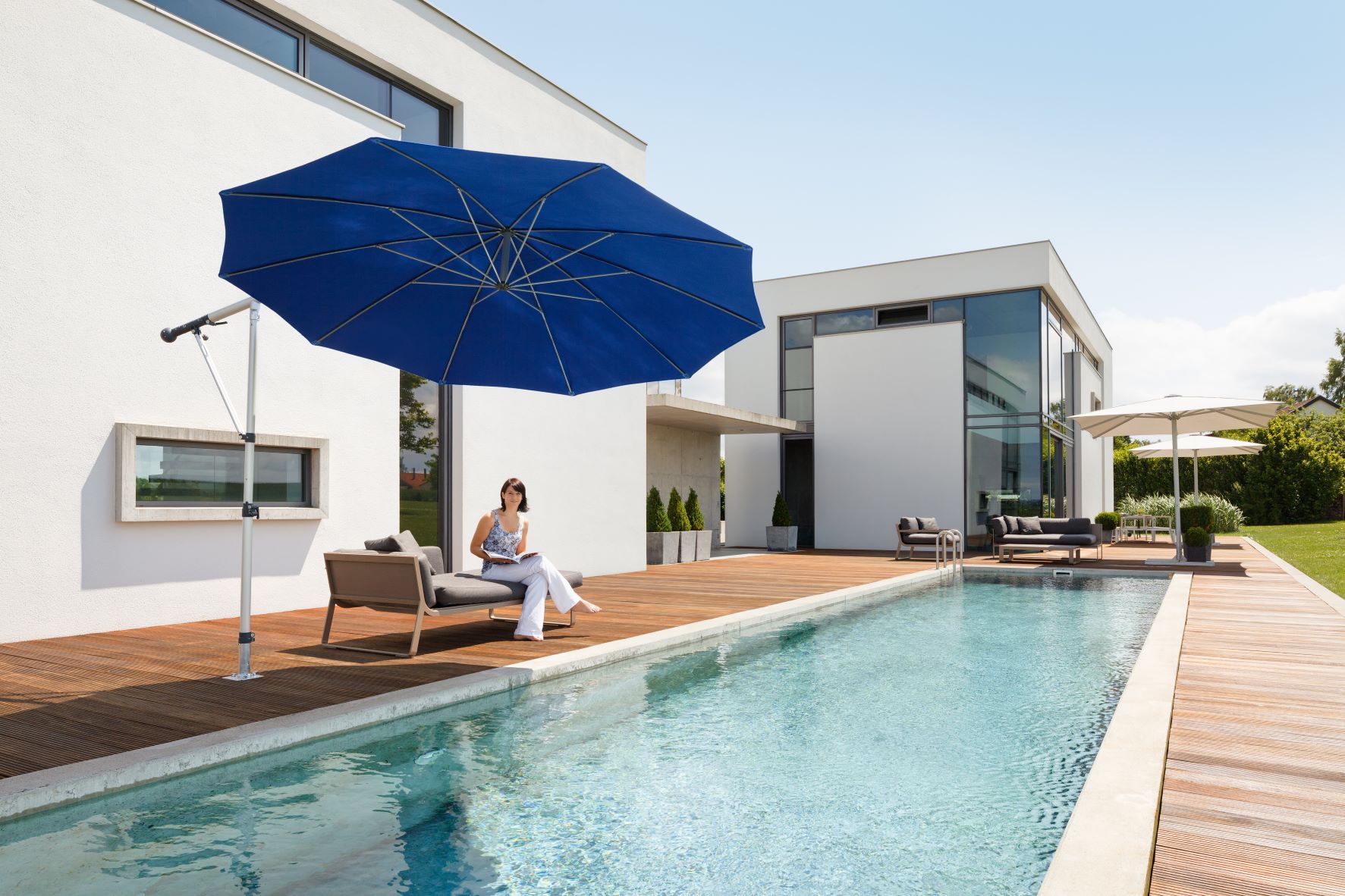 modernes Haus mit einem Swimmingpool eingefasst in einer Holzterrasse, Sonnenschirm