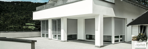 Ein Ausschnitt der unteren Etage eines modernen Hauses mit unterschiedlichen Fenster Größen und breiten ausgestattet mit Rollläden der Firma Roma.